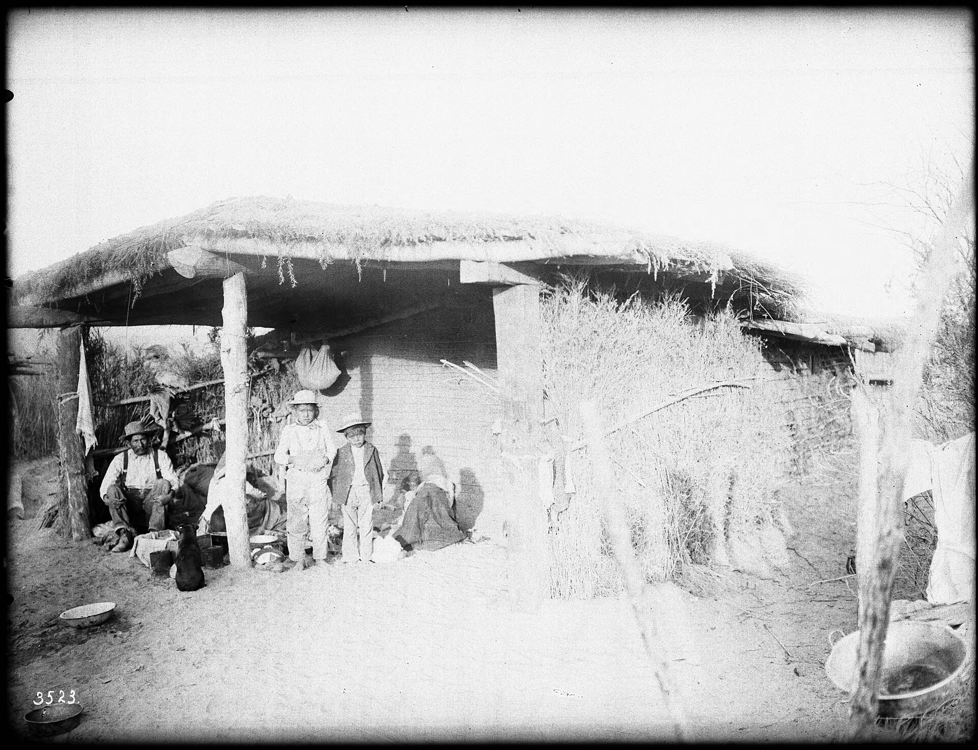 A Chemehuevi family seated at their brush dwelling in the desert, photographed around 1900.